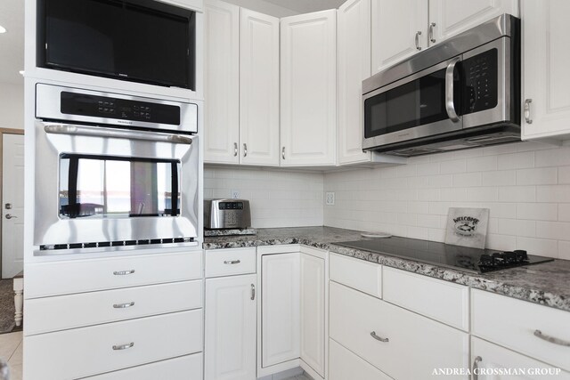 1761 S Shore Dr, Holland, MI 49423 - kitchen featuring white cabinetry, stone counters, black appliances, and decorative backsplash