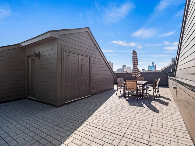 view of patio featuring outdoor dining space, an outbuilding, and a city view