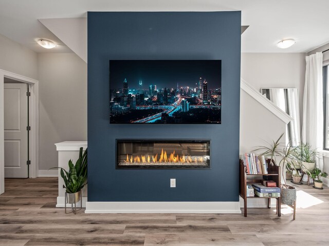 interior details featuring baseboards, a glass covered fireplace, and wood finished floors