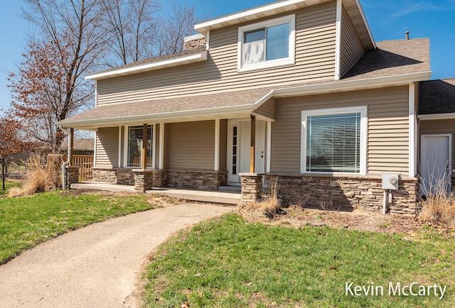 view of front of house featuring a front lawn, stone siding, a porch, and roof with shingles