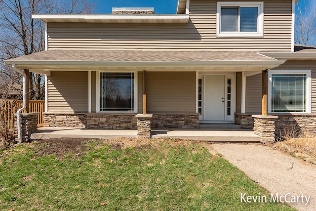 view of front of house featuring stone siding, a porch, and roof with shingles