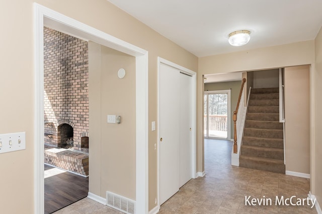 hall featuring baseboards, visible vents, and stairway