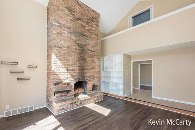 unfurnished living room with baseboards, visible vents, wood finished floors, and a brick fireplace