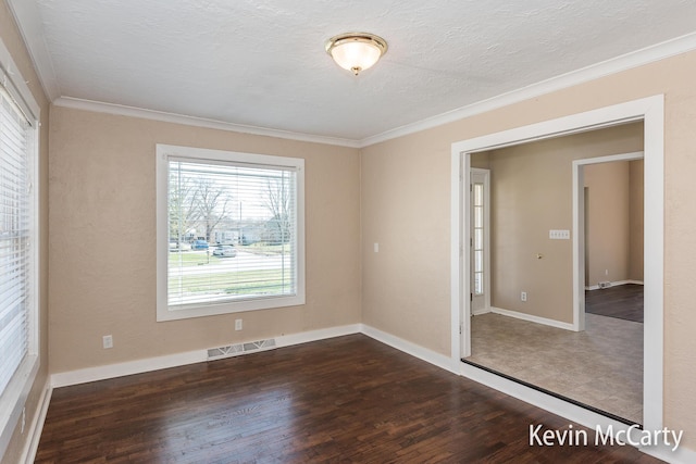 unfurnished room with wood finished floors, a textured ceiling, baseboards, visible vents, and ornamental molding