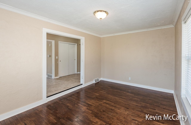 spare room featuring crown molding, baseboards, a textured ceiling, visible vents, and wood finished floors
