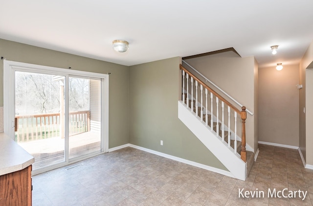 unfurnished room featuring baseboards, visible vents, and stairway