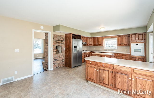 kitchen featuring light countertops, stainless steel fridge, oven, and visible vents