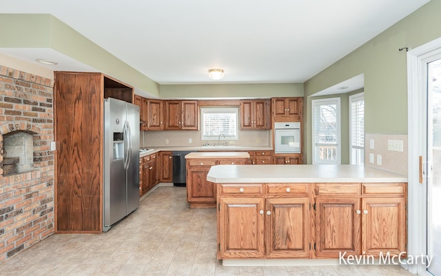 kitchen with light countertops, brown cabinetry, a peninsula, and appliances with stainless steel finishes