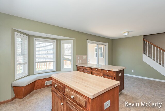 kitchen featuring baseboards, visible vents, brown cabinetry, and light countertops