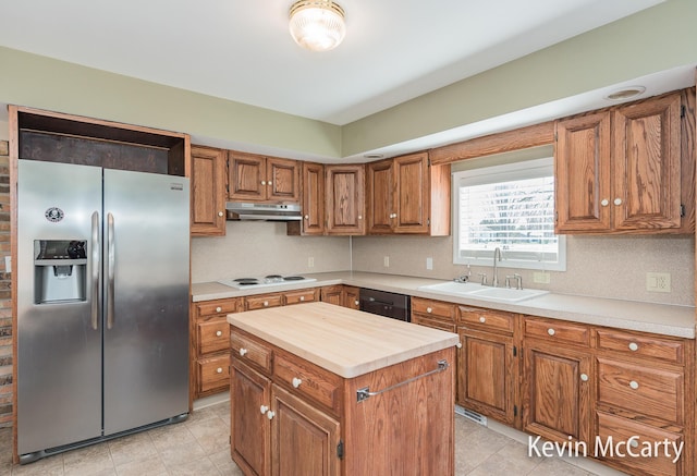 kitchen featuring brown cabinets, under cabinet range hood, a sink, stainless steel fridge with ice dispenser, and white electric cooktop