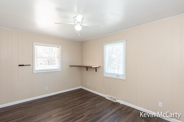 empty room with a ceiling fan, dark wood-style floors, baseboards, and visible vents