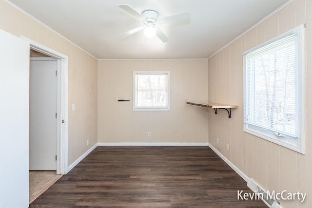 empty room with a healthy amount of sunlight, a ceiling fan, and dark wood finished floors