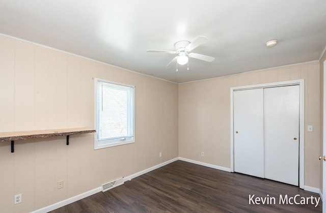 unfurnished bedroom featuring baseboards, dark wood finished floors, visible vents, a ceiling fan, and a closet