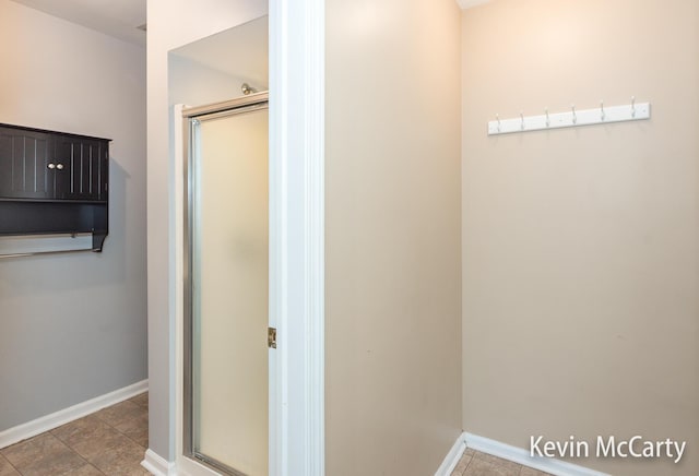 bathroom featuring a shower stall and baseboards