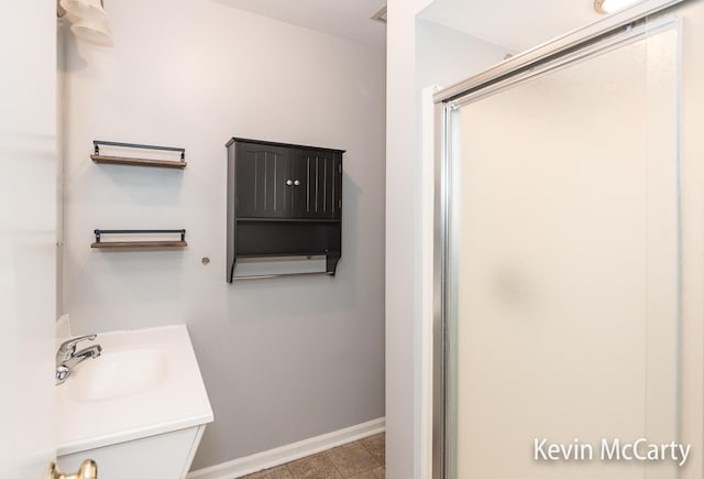full bath with vanity, baseboards, and a shower stall
