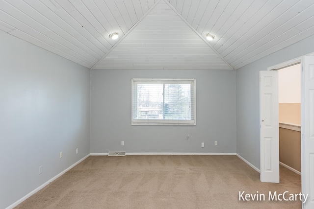 empty room with vaulted ceiling, wooden ceiling, baseboards, visible vents, and light carpet