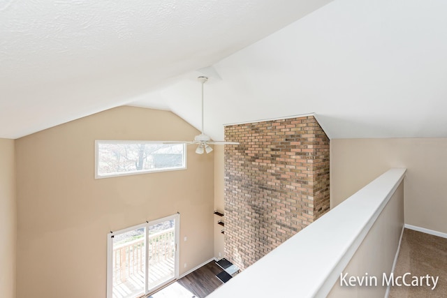 corridor featuring baseboards, a healthy amount of sunlight, and vaulted ceiling