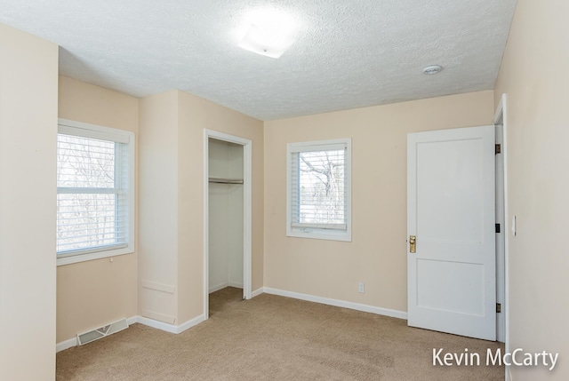 unfurnished bedroom featuring baseboards, visible vents, carpet floors, and a textured ceiling