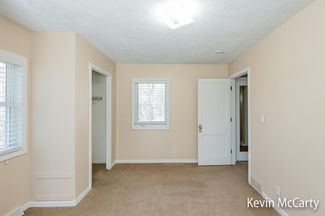 unfurnished bedroom with baseboards, a textured ceiling, and light carpet