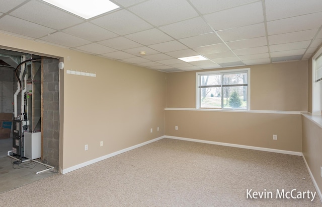 basement featuring heating unit, baseboards, and a paneled ceiling