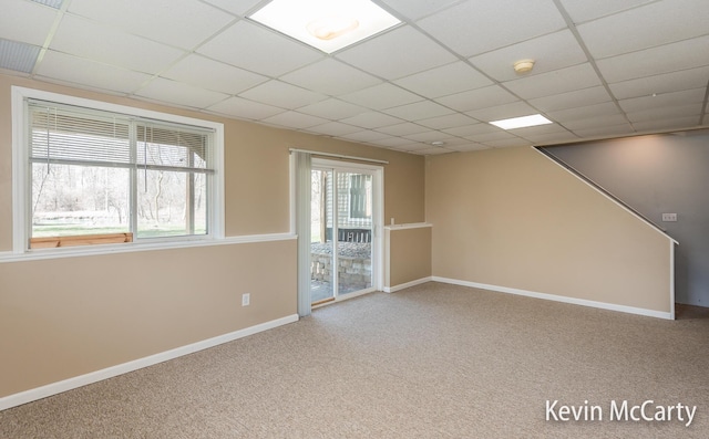 interior space with baseboards, carpet flooring, and a paneled ceiling