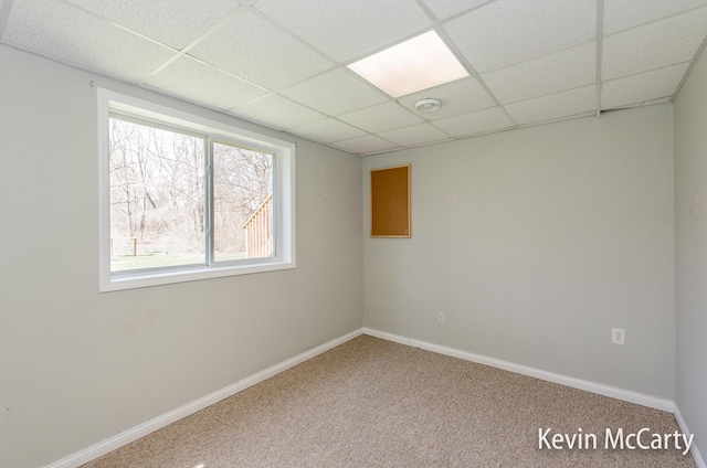 spare room with a drop ceiling, carpet flooring, and baseboards