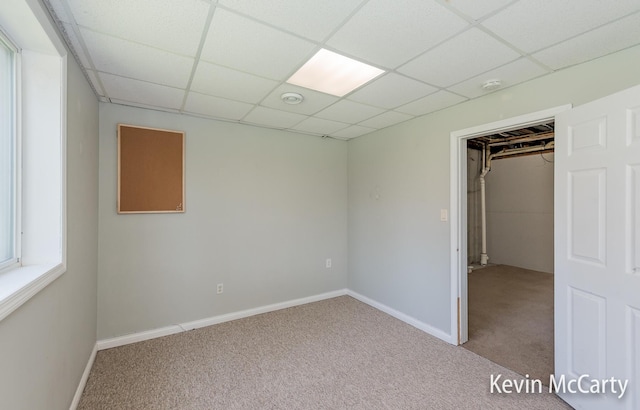 unfurnished bedroom featuring a drop ceiling, carpet, and baseboards