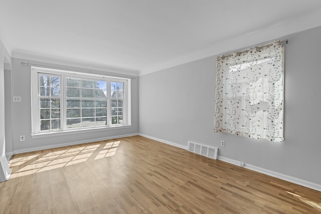 empty room with baseboards, wood finished floors, and visible vents