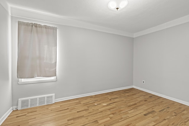 empty room with baseboards, wood finished floors, and visible vents