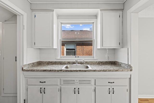 kitchen featuring decorative backsplash, white cabinetry, and a sink
