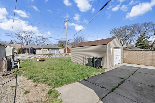 view of yard featuring fence, driveway, an outdoor structure, and a garage