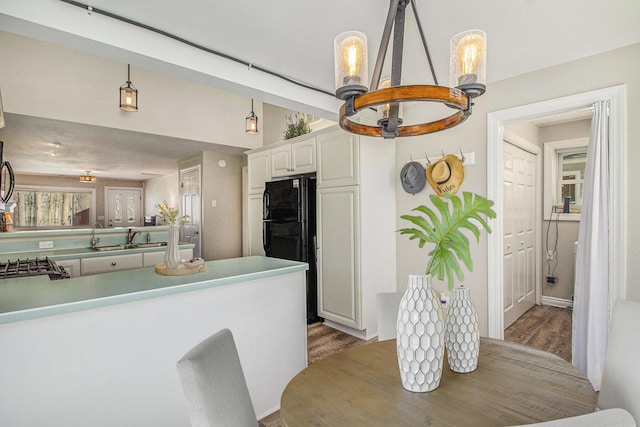 kitchen featuring a sink, white cabinets, wood finished floors, and freestanding refrigerator