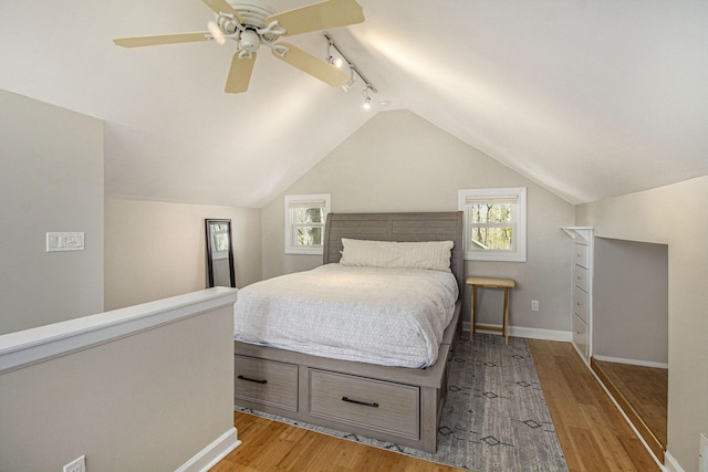 bedroom with baseboards, vaulted ceiling, light wood-style flooring, and ceiling fan
