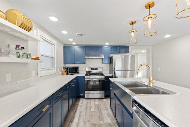kitchen featuring blue cabinets, light wood-style flooring, under cabinet range hood, appliances with stainless steel finishes, and a sink