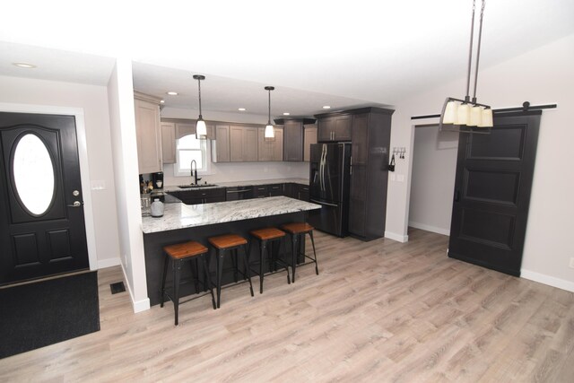 28 Hunting Trail Ave, Quincy, MI 49082 - kitchen featuring a peninsula, light stone countertops, light wood-type flooring, black fridge, and a breakfast bar area