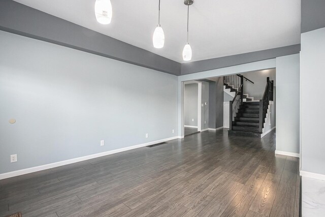 101 E 4th St, Buchanan, MI 49107 - unfurnished living room with dark wood-type flooring, baseboards, stairs, and visible vents