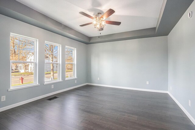 101 E 4th St, Buchanan, MI 49107 - spare room with a tray ceiling, baseboards, dark wood-style floors, visible vents, and a ceiling fan
