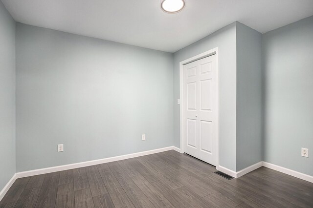 101 E 4th St, Buchanan, MI 49107 - unfurnished bedroom with baseboards, visible vents, and dark wood-type flooring