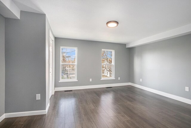 101 E 4th St, Buchanan, MI 49107 - spare room featuring dark wood-type flooring, baseboards, and visible vents