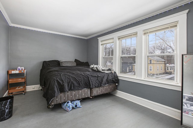 bedroom featuring baseboards, crown molding, and wood finished floors