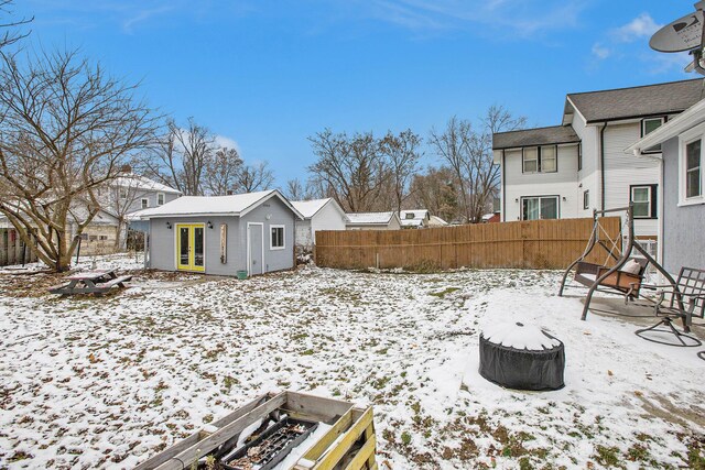 yard covered in snow with an outbuilding, a fenced backyard, and french doors