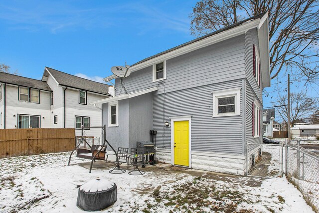 snow covered back of property featuring a fenced backyard