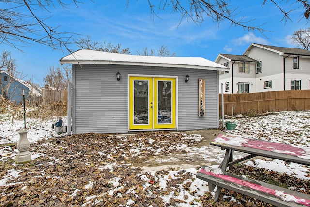 snow covered back of property featuring an outbuilding and fence