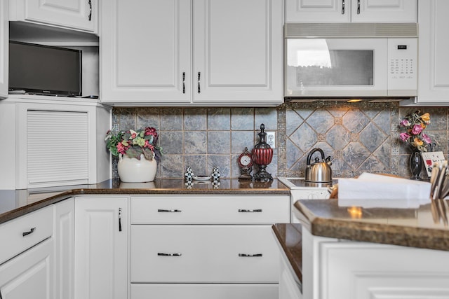 4284 Fairway Ln, Jackson, MI 49201 - kitchen featuring backsplash, white microwave, white cabinetry, and dark stone counters