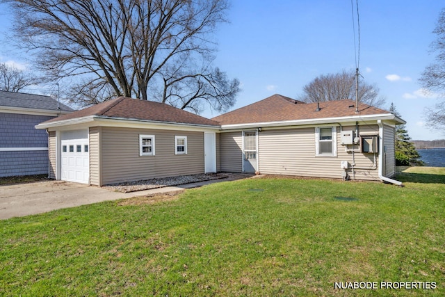 back of property featuring roof with shingles, concrete driveway, a garage, and a yard