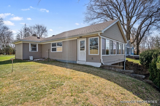 view of front of home with a sunroom, roof with shingles, and a front lawn