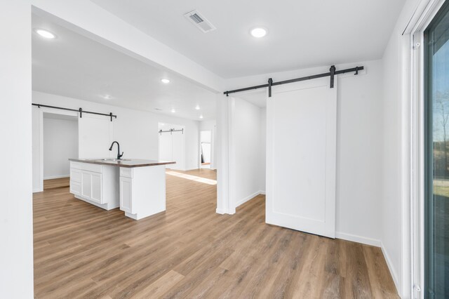 10282 7 Mile Rd, Evart, MI 49631 - unfurnished living room featuring recessed lighting, a sink, a barn door, visible vents, and light wood-style flooring