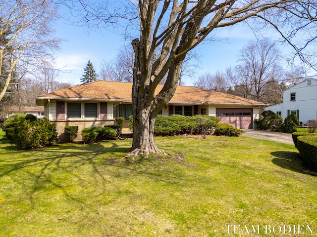 ranch-style house featuring a front lawn, an attached garage, and concrete driveway
