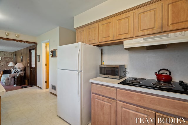 kitchen featuring freestanding refrigerator, black electric stovetop, under cabinet range hood, stainless steel microwave, and visible vents