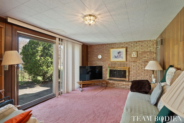 living area with a fireplace, wooden walls, carpet, and brick wall